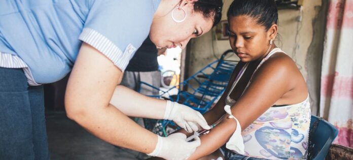 Uma profissional de saúde coleta amostras de sangue de uma mulher que já havia contraído dengue (arquivo)