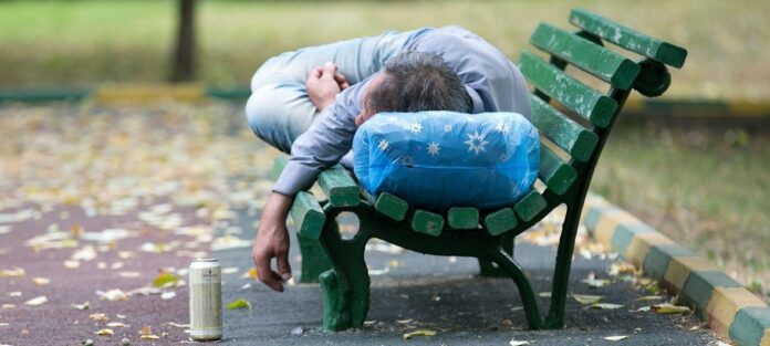 Um homem embriagado está dormindo em um banco de um parque Um homem embriagado está dormindo em um banco de um parque